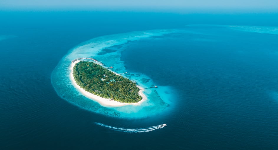 Aerial view of NH Collection Maldives Reethi Resort island surrounded by turquoise lagoon – Stay Longer Special offer