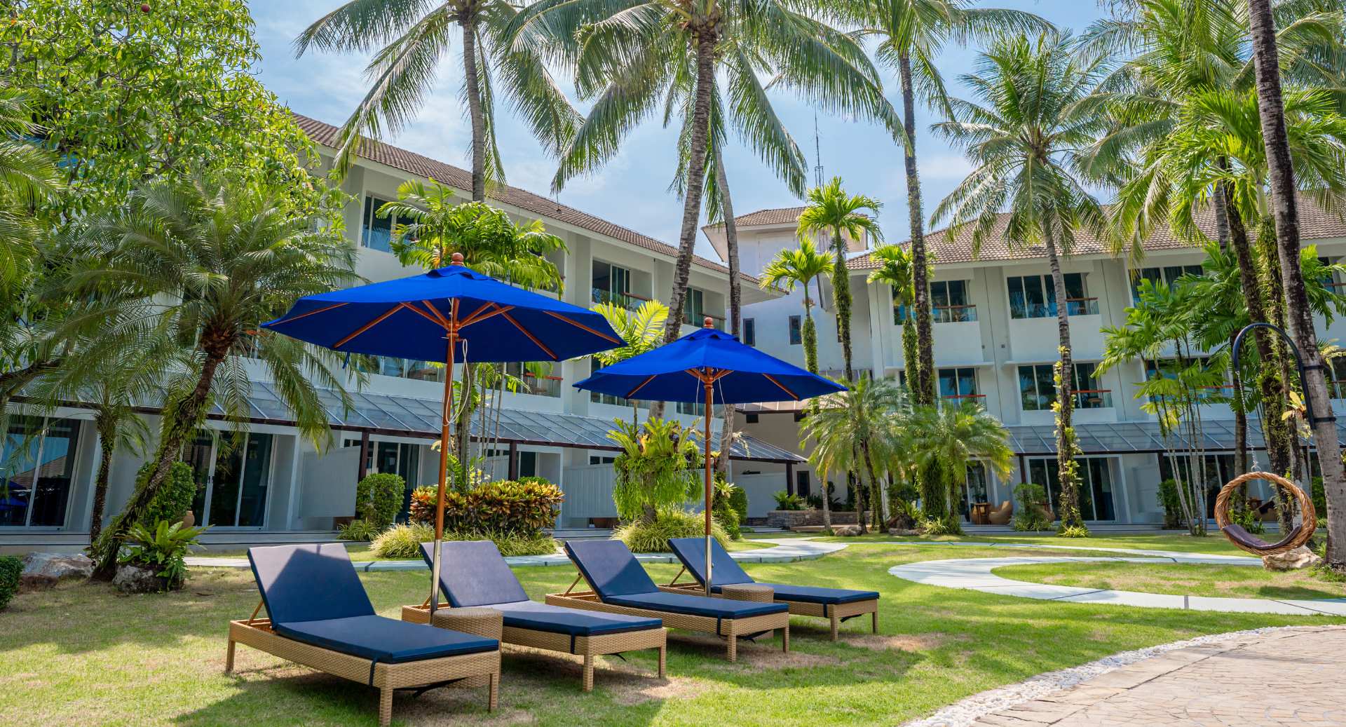 Resort garden area at NH Boat Lagoon Phuket with sun loungers and tropical landscaping