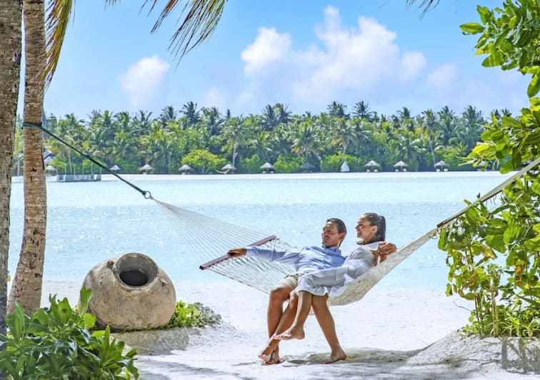 Couple sitting on the beach at Naladhu Maldives