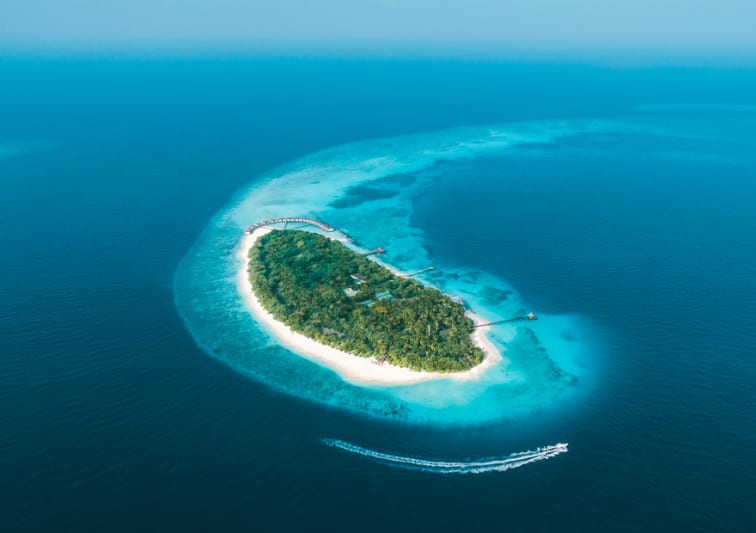 Aerial view of NH Collection Maldives Reethi Resort island surrounded by turquoise lagoon – Stay Longer Special offer