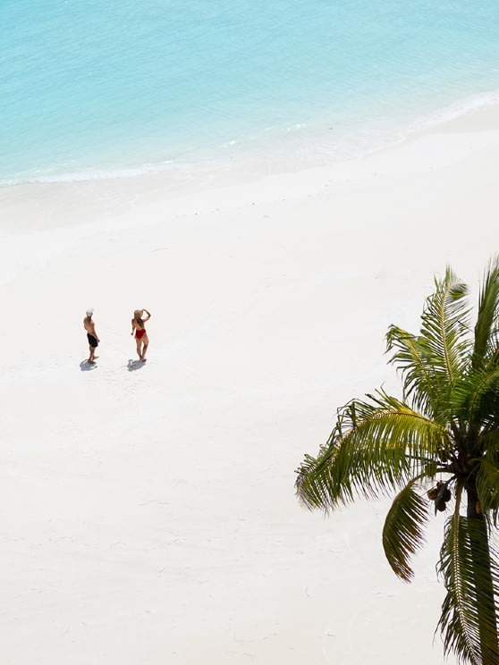 Couple walking along a white-sand beach with turquoise waters at Niyama Maldives, part of the Maldives Stay and Dine offer.