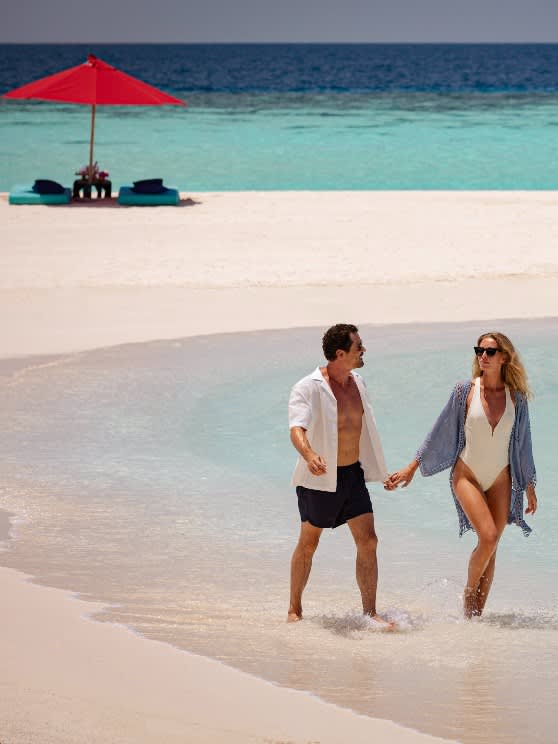 Couple enjoying a stroll on the sandbank at NH Collection Maldives Havodda Resort