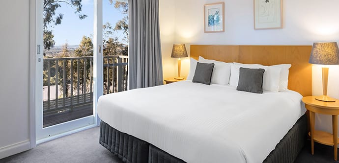 Hunter Valley resort bedroom with king size bed near window looking out over forest and golf course