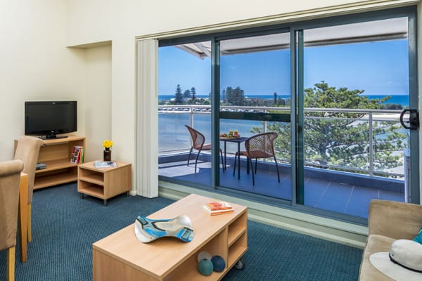 hotel apartment living room with television and balcony with views of The Entrance nsw