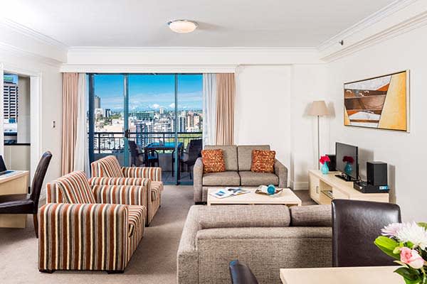 spacious living room area in 3 bed hotel apartment based in Sydney CBD with large balcony and comfortable furniture
