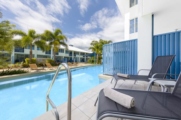 balcony with comfortable furniture leading to large swimming pool at Oaks Lagoons holiday resort in Port Douglas