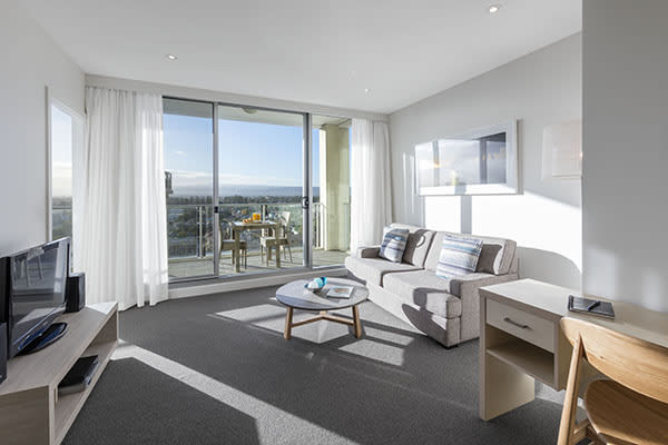 Best Glenelg hotels with large living room with Foxtel on TV, big, comfortable couches and private balcony outside with views of Glenelg and the ocean