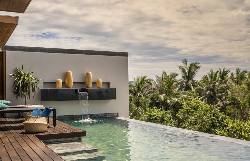 Sun deck and infinity pool of Ocean View Pool Villa with water feature and view of trees